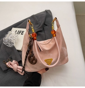 Detail of pink nylon shoulder bag with amber beaded handle and gold logo plaque