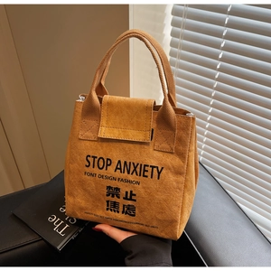 Detail of waterproof Dupont paper tote bag with STOP ANXIETY print in caramel brown