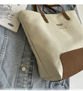 Detail of canvas tote bag with brown faux leather corners and printed SOBAG logo text