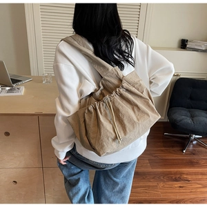 Rear view of khaki drawstring tote bag with natural pleats shown in a home office setting