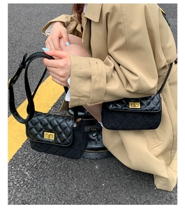 Detail of classic black quilted crossbody bag with golden lock and adjustable strap