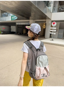 Detail of multi-color nylon backpack with drawstring pocket worn in an urban street setting