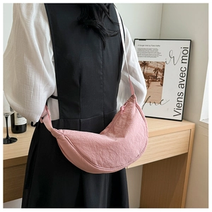 Detail of pink nylon crescent bag with adjustable strap shown in a lifestyle setting