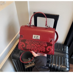 Detail of red faux leather handbag with deep red floral embossing and silver twist lock