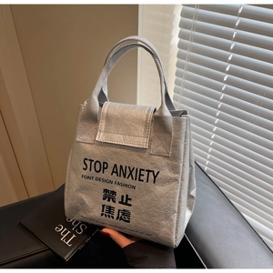 Detailed shot of silver DuPont paper tote bag featuring black STOP ANXIETY slogan print