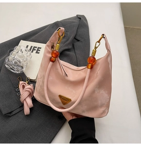 Detail of pink marble pattern bag with amber beaded handle and gold hardware