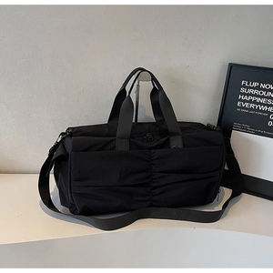 Detail of black travel bag featuring vertical pleats and durable nylon texture