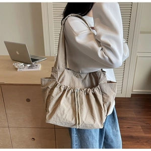 Detail of beige large tote bag featuring functional drawstring front pocket for daily commute