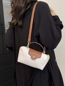 White nylon dumpling bag with brown leather trim and golden hardware in crossbody style