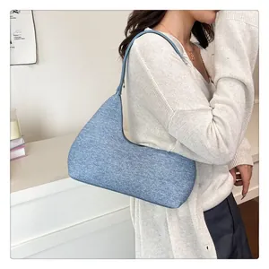Detail view of a blue denim crescent underarm bag with a wide strap for casual wear