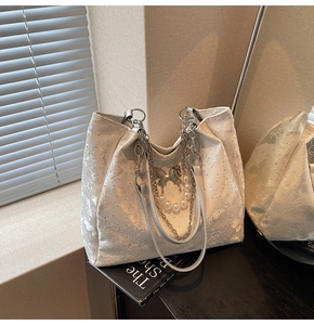 Détail du sac cabas blanc texturé avec chaîne argentée, perles et pendentif papillon