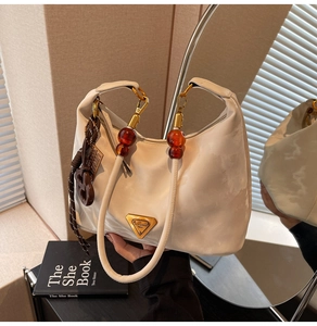 Close-up of cream hobo bag with amber bead handle and golden triangle logo detail