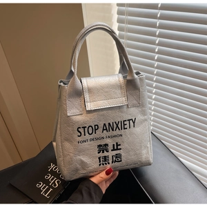 Detail of silver metallic tote bag with Stop Anxiety slogan and hand-held strap