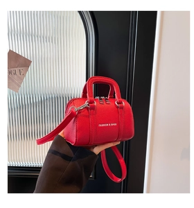Gros plan sur un mini sac Boston rouge en cuir grainé avec texte de mode élégant