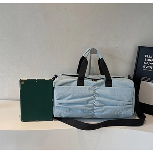 Detail of light blue pleated travel bag showing spacious capacity next to a tablet