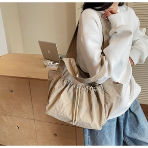Detail of khaki nylon tote bag showing drawstring closure and side pockets in office setting