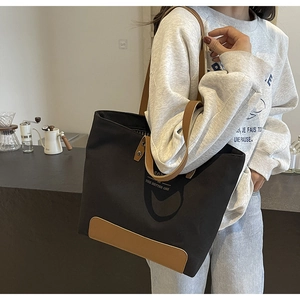 Detail of canvas tote bag with brown leather base and 'The Better One' print