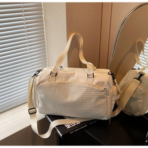 Detailansicht der cremeweißen Reisetasche mit karierter Textur und Stickerei-Logo