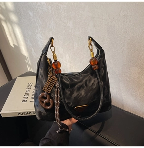 Detail of black textured nylon bag with amber beads and vintage charms hanging on side