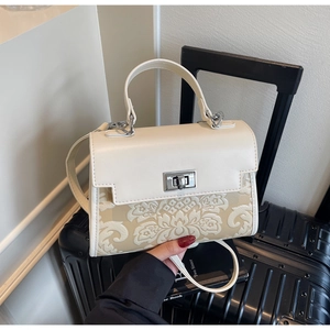 Detail of cream white faux leather bag with elegant floral embossing and metal buckle