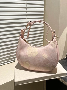 Floral print hobo bag in pink and cream with gold hardware on a book display