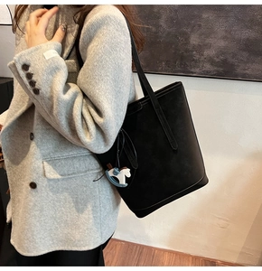 Close-up of black matte tote bag featuring a decorative blue and white horse pendant