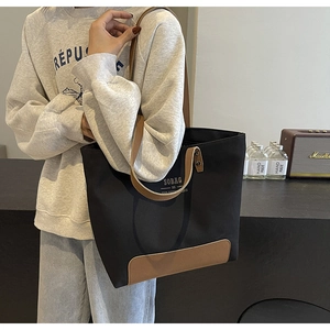 Close-up of black canvas tote bag with brown leather handles and vintage interior styling