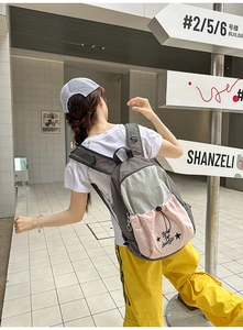 Rear view of a stylish grey and pink three-tone backpack featuring a star print on a city street