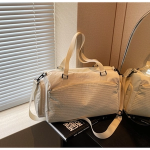 Detail der cremeweißen Reisetasche mit Steppmuster und Markenlogo mit Trageriemen