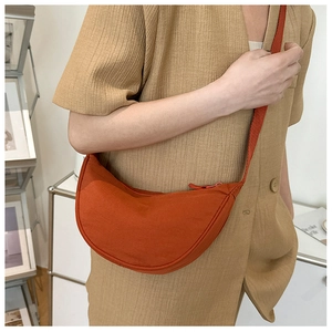 Detail of a casual bright orange nylon crescent crossbody bag with a wide shoulder strap