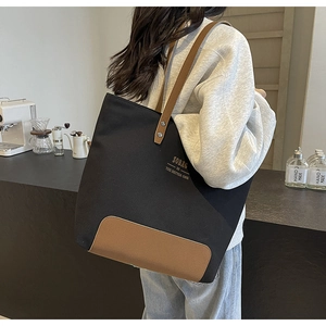 Lifestyle view of a large canvas tote bag with brown leather straps worn by a model