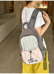 Detail of grey student backpack with contrast pink drawstring pocket and star print