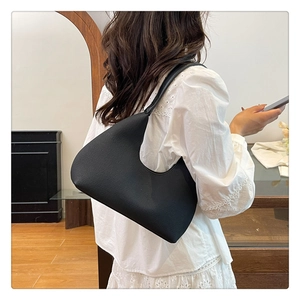 Side view of black crescent underarm bag with textured leather on a female model