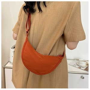 Rear view of a casual burnt orange nylon half-moon crossbody bag with wide shoulder strap