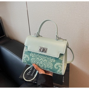 Close-up of mint green leather handbag featuring floral embossing and silver twist lock