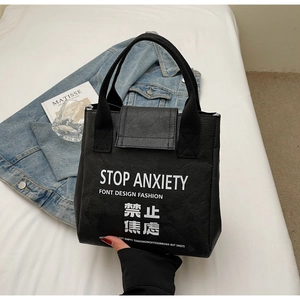Detail view of black DuPont paper tote bag with Stop Anxiety print and crinkled texture