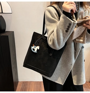 Minimalist black matte tote bag with small horse charm shown on a female model