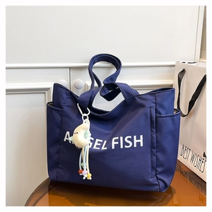 Détail d'un sac cabas en nylon bleu marine avec inscription et pendentif lune