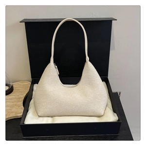 Detail of a minimalist cream hobo bag placed inside a premium gift box with dust bag
