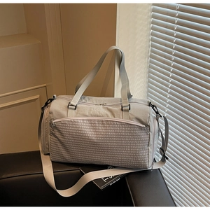 Detailansicht der grauen Reisetasche mit Netztasche auf einem Ledersofa