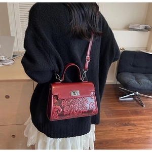 Detailed close-up of 3D floral relief pattern on a vintage dark red leather handbag