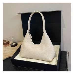Detail view of a cream hobo bag with woven texture inside an elegant black gift box