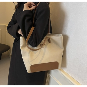 Canvas tote bag with leather trim detail and shoulder strap shown on a model