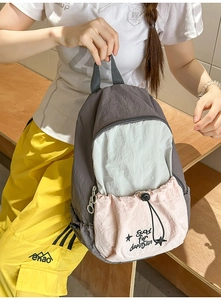 Close-up of dual-tone grey and pink school backpack with Good for dancin embroidery