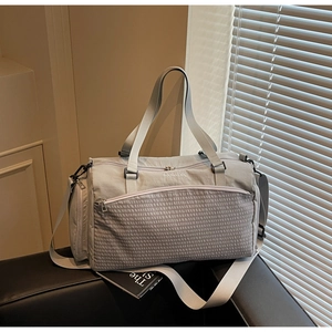 Detail der grauen Reisetasche mit strukturierter Reißverschlusstasche und Gurt