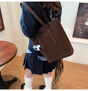Close-up of brown textured leather bucket bag featuring a blue and white horse charm