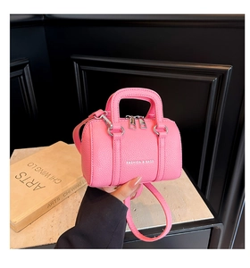 Détail d'un mini sac cylindre rose avec texture litchi et fermetures éclair argentées