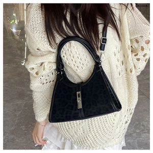 Close-up of black bucket bag with dark leopard texture and silver buckle worn by model