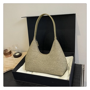 Detail of hobo bag in khaki tweed fabric with leather strap inside a gift box