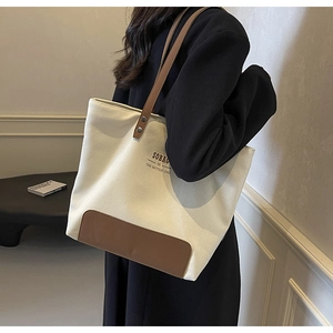 Close-up of minimalist canvas tote bag featuring brown leather trim and SOBAG logo